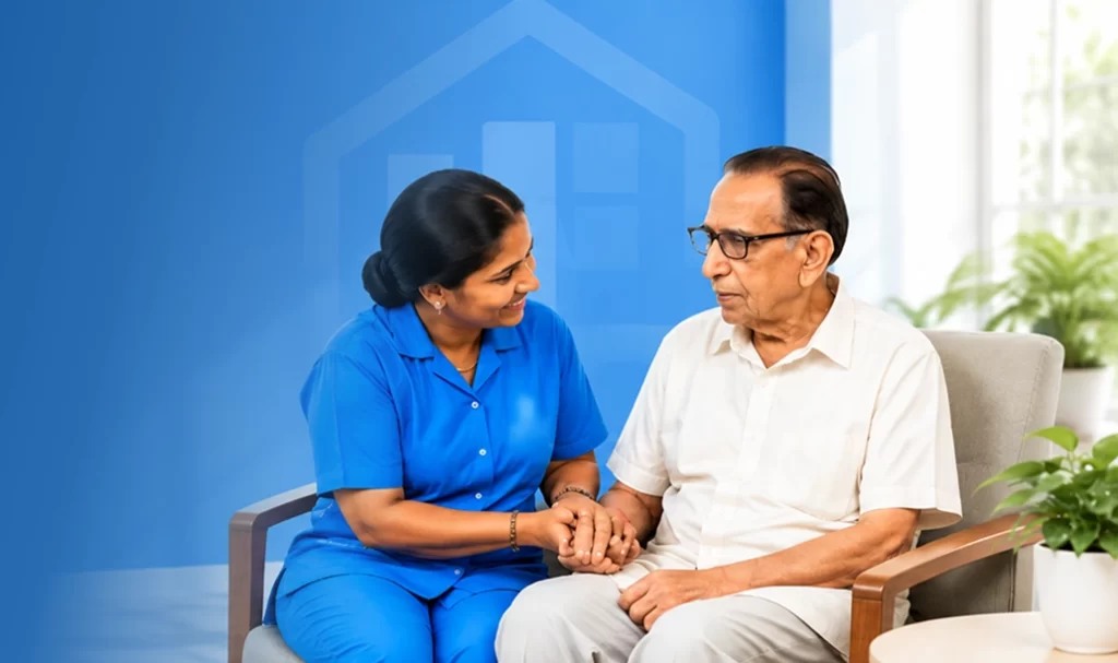 Caregiver in blue scrubs holding an elderly man's hands while talking with him